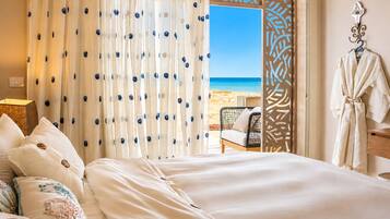 Une chambre d’hôtel avec un lit, une vue sur la plage et un peignoir accroché au mur.