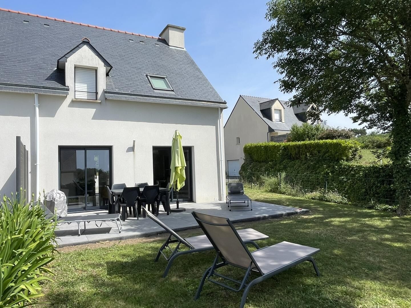 Une maison moderne dotée d’un patio, d’un espace salon extérieur et d’une pelouse bien entretenue.