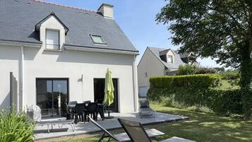 Une maison moderne dotée d’un patio, d’un espace salon extérieur et d’une pelouse bien entretenue.