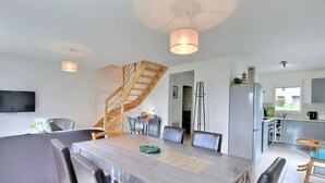 A modern kitchen with a built-in oven, a dining area with a large table and chairs, and a staircase leading to an upper level.
