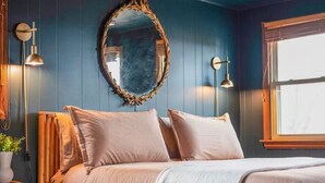 Un dormitorio con una cama de madera, un espejo grande y dos lámparas fijadas a la pared.