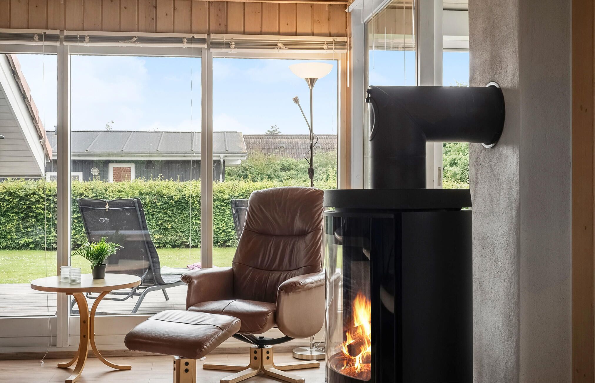 A cozy room with a fireplace, leather armchair, and a small table with a potted plant.