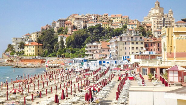 A beach with rows of sunbeds and umbrellas, a hotel with a red roof, and buildings with balconies in the background. - Gorgeous home in Ponti di Pornassio (Ponti di Pornassio)