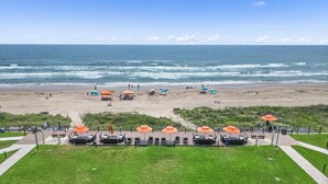A beach with umbrellas, lounge chairs, and a view of the ocean. - Solare Tower Sunset Panorama Paradise (South Padre Island)