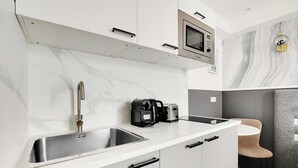 A modern kitchen with a stainless steel sink, a coffee maker, and a microwave.