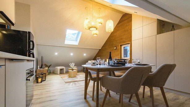 Une cuisine moderne avec un coin repas, dotée d’un plafond en bois, d’une lucarne et de luminaires suspendus.