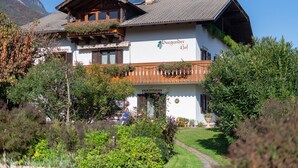 A two-story building with a wooden balcony, a sign reading 'Burgunder Hof,' and a mountain backdrop. - 723A Apartment Burgunderhof (Termeno sulla strada del vino)