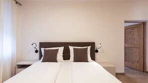 Un dormitorio con una cama, dos mesitas de noche y una puerta de madera.