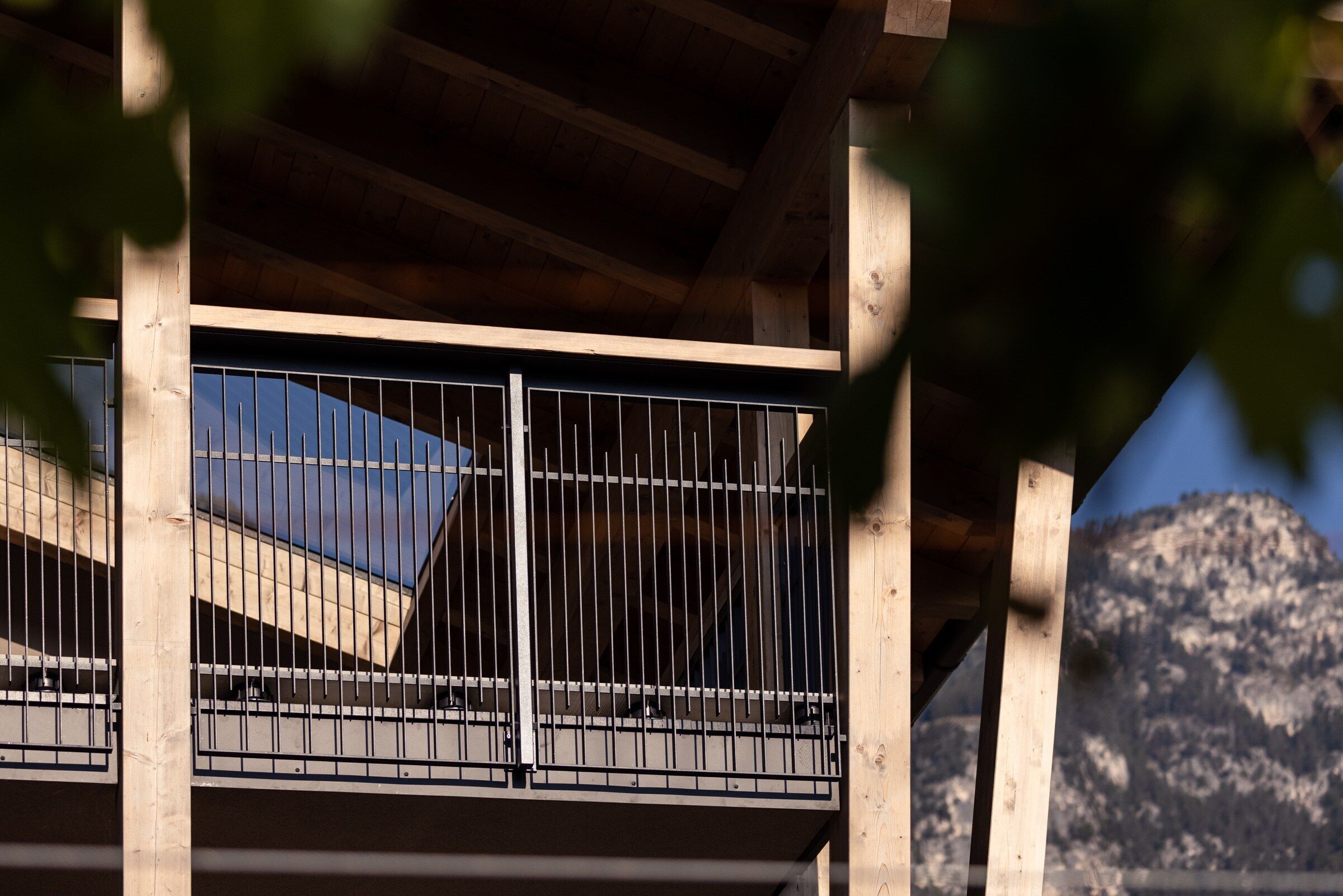 A wooden balcony with metal railings and a view of a mountain.
