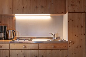 A kitchen with wooden cabinets, a stainless steel sink, and a built-in light above the countertop.