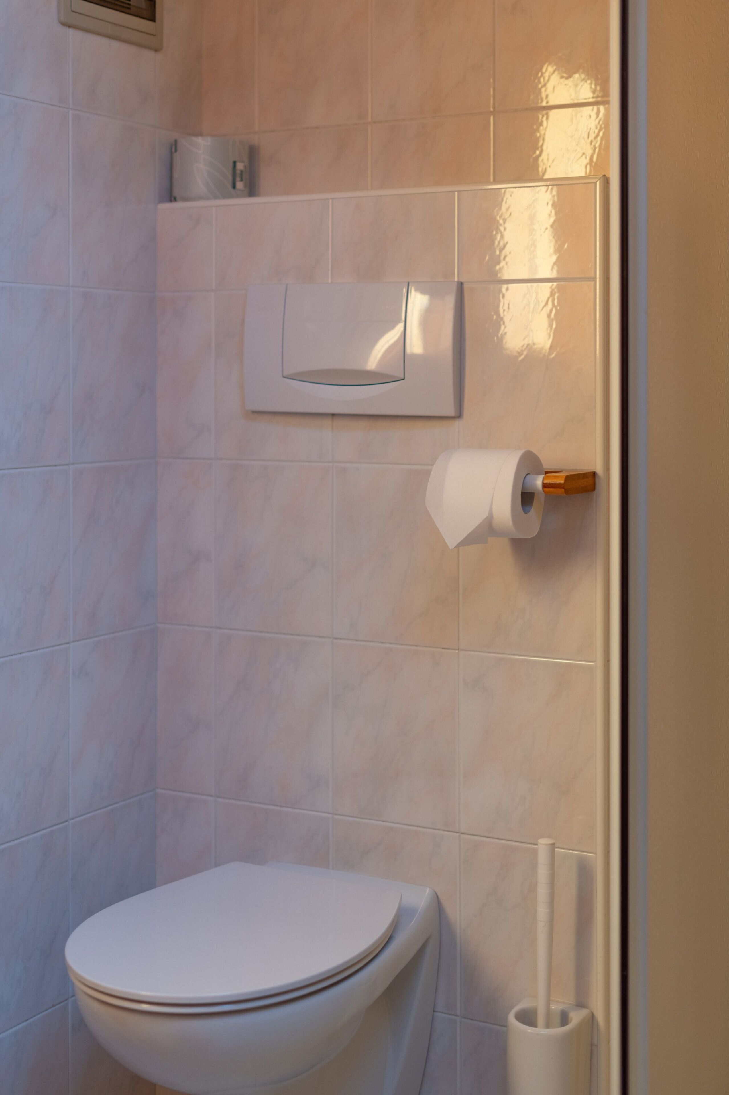 Ein Badezimmer mit Toilette, Papierhandtuchspender und Toilettenpapierhalter an der Wand.