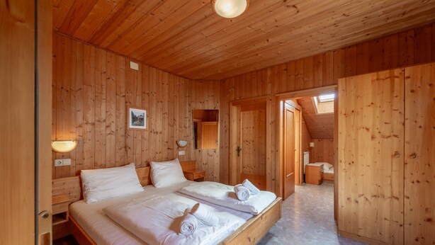 Una camera in legno con un letto, un comodino, una lampada a parete e un quadro incorniciato.