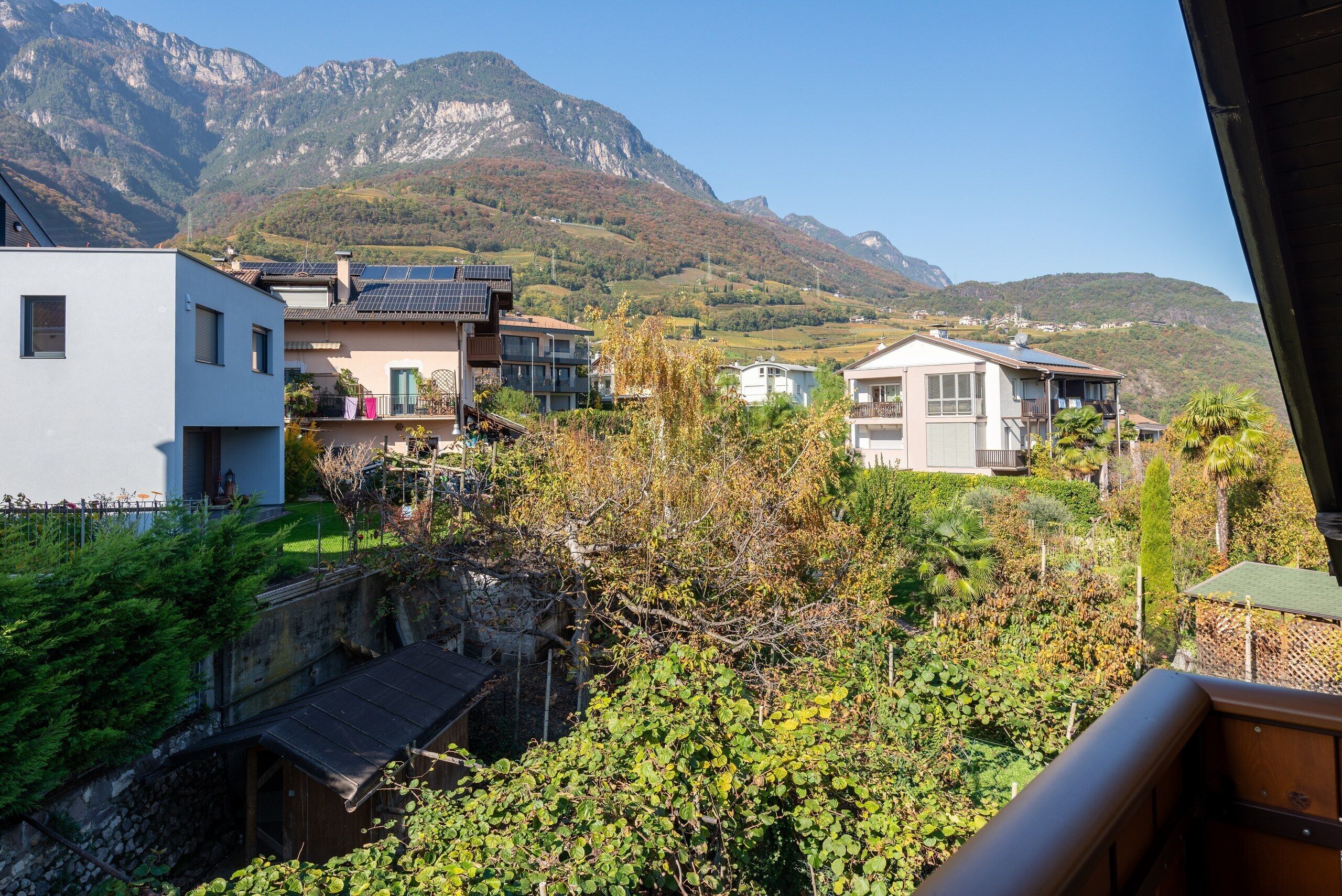 Ein Wohngebiet mit modernen Häusern, einer Steinmauer und einem Berg im Hintergrund.