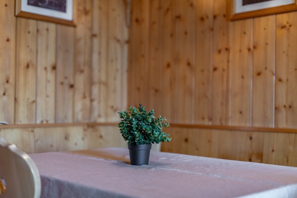 Una habitación con paredes de paneles de madera, una mesa con mantel blanco y una planta en maceta sobre la mesa.