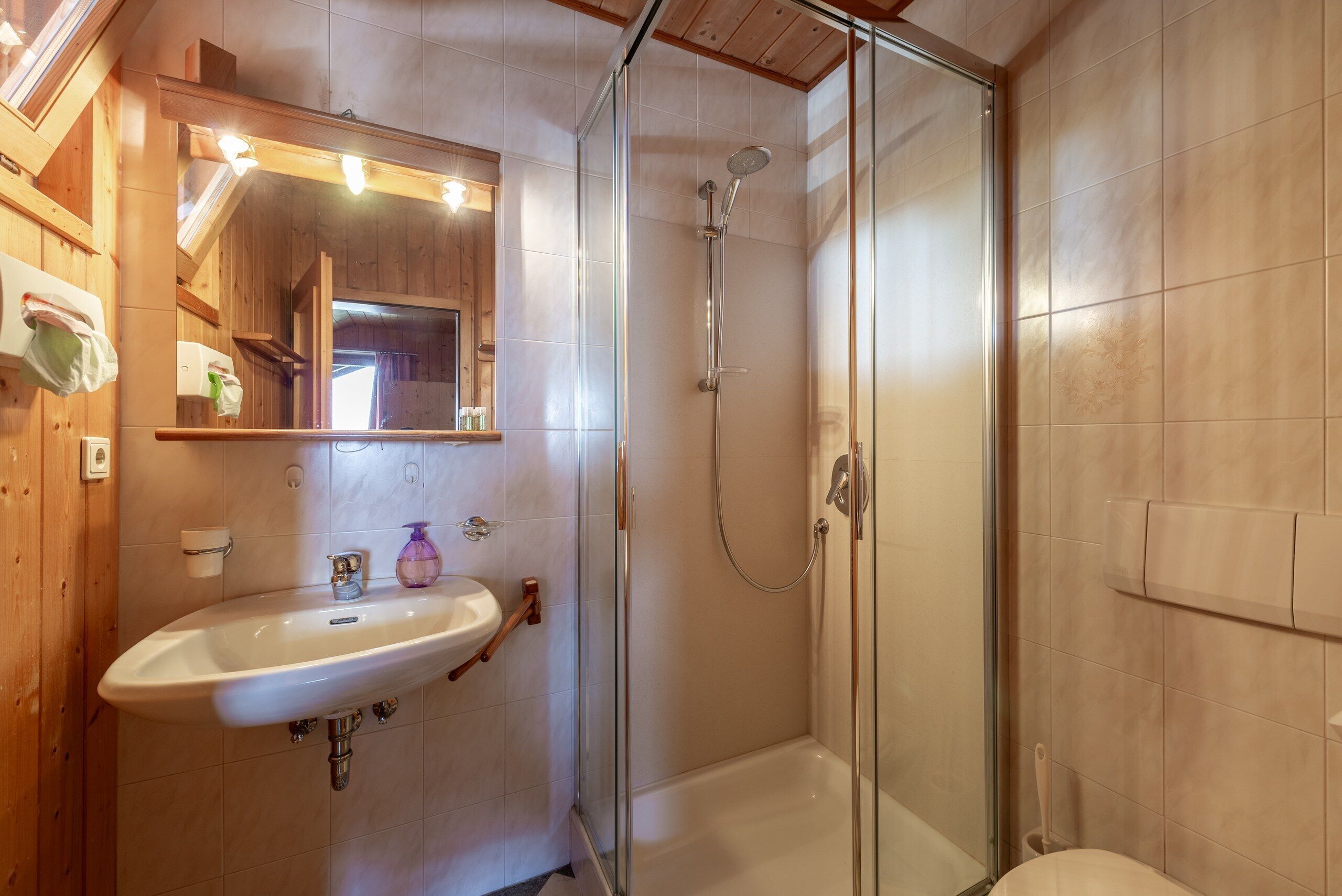 Ein Badezimmer mit einer Duschkabine, einem weißen Waschbecken und einem Spiegel darüber.