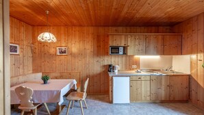 Una cucina compatta con pareti in legno, un'area pranzo con tavolo e sedie, un forno a microonde e un lavello.