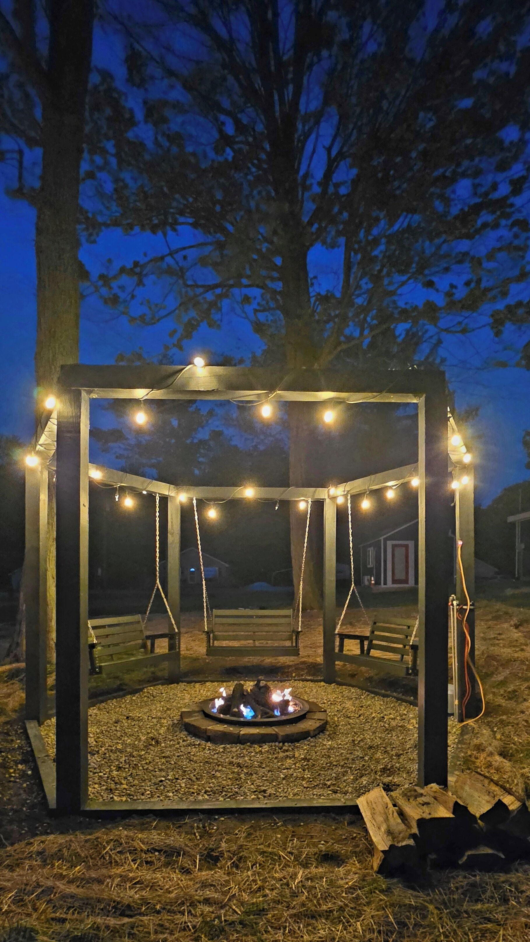 Un belvédère illuminé de guirlandes lumineuses, un foyer et des balançoires.