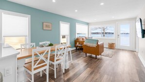 Una cocina moderna con armarios blancos, una mesa de comedor de madera y sillas blancas.