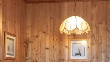 Un interno in legno con un tavolo, sedie, una lampada a sospensione e quadri appesi al muro.