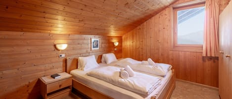 Une pièce en bois avec un lit, des tables de chevet et une fenêtre.