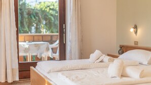 Ein Hotelzimmer mit einem Bett, einem Tisch und Blick auf Grünfläche.