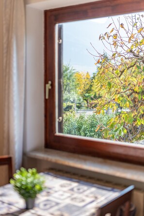 Une fenêtre donnant sur un arbre aux feuilles jaunes, un ciel dégagé et une porte dotée d’une poignée.