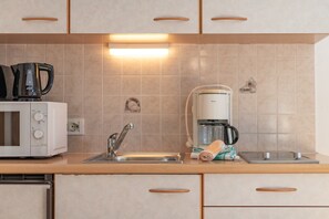 Una cocina equipada con microondas, cafetera y lavamanos.