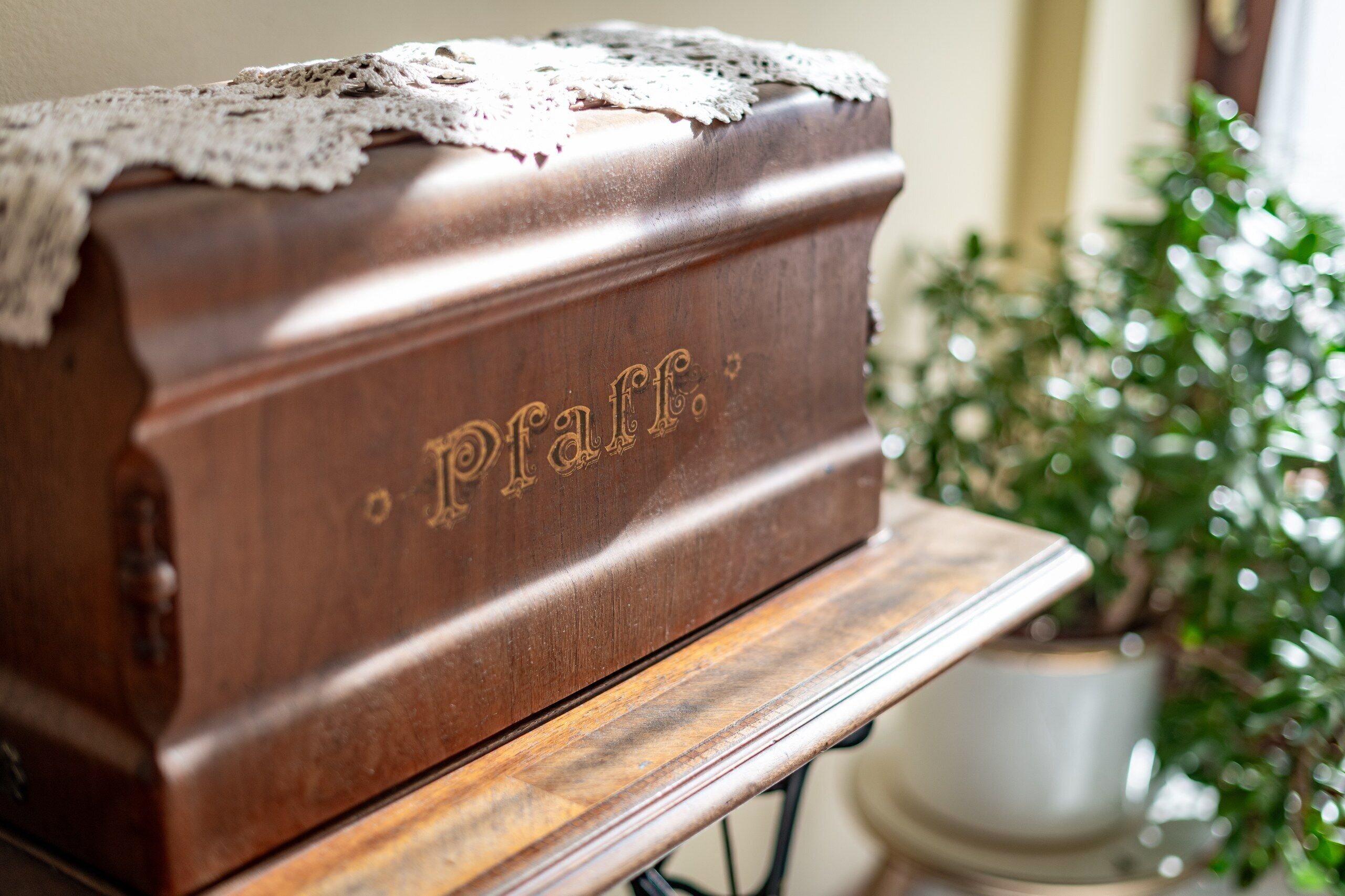 Une boîte en bois portant l’inscription « Pfaff », gravée sur le dessus, posée sur une table en bois.
