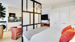 Une chambre d’hôtel moderne équipée d’un grand lit, d’un bureau et d’une kitchenette.