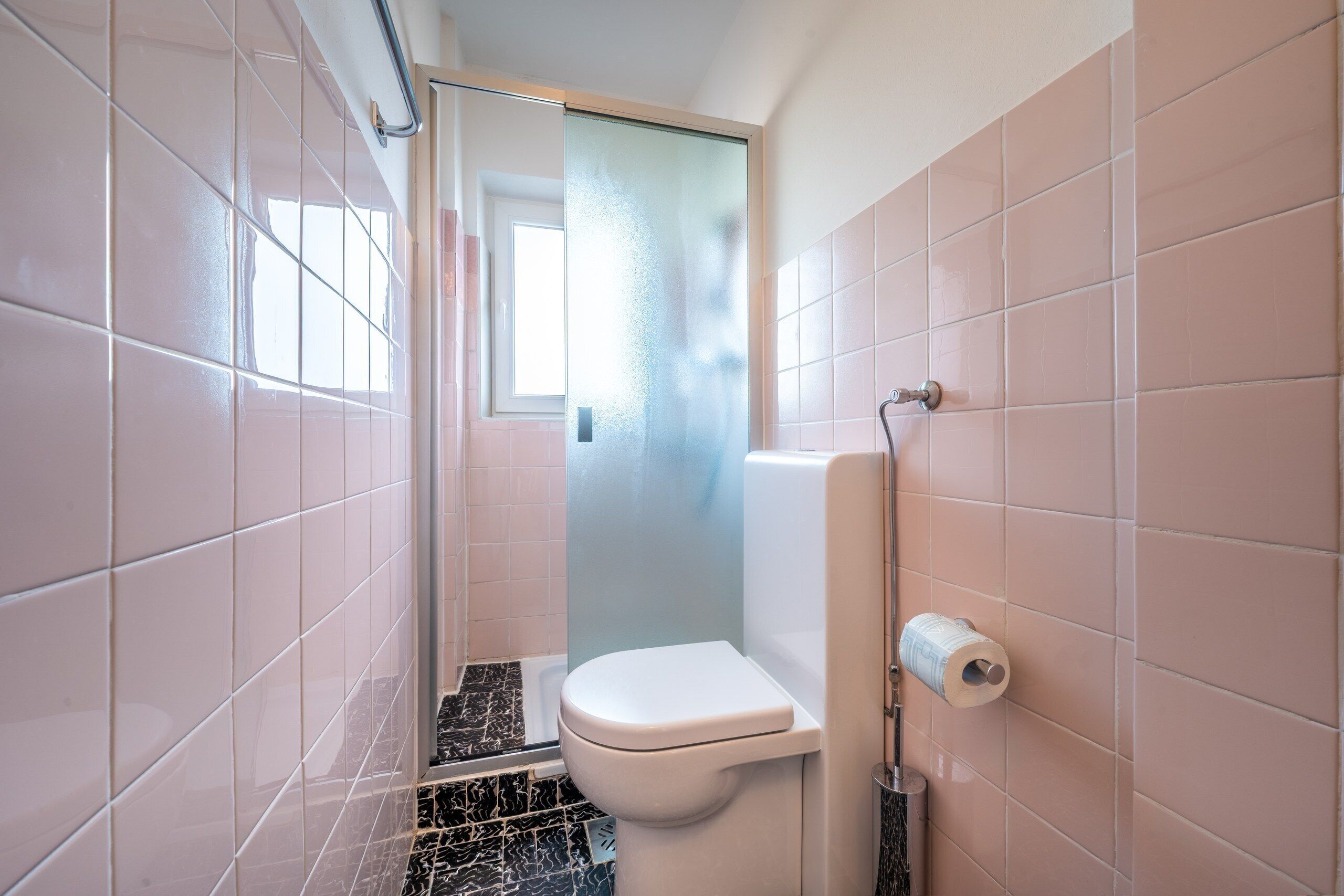 Une petite salle de bain comprenant des toilettes, une douche et un porte-rouleau de papier toilette.