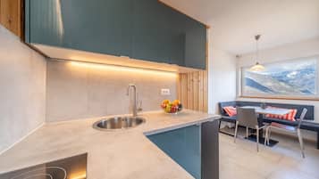 Eine moderne Küche mit integriertem Spülbecken, einem Essbereich mit Tisch und Stühlen sowie Bergblick durch ein Fenster.