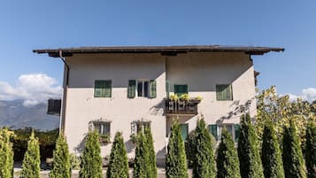 Un edificio de dos pisos con un balcón, rodeado de árboles altos y delgados.