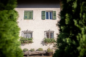 Un bâtiment doté de deux fenêtres, chacune ornée de volets verts et de jardinières.