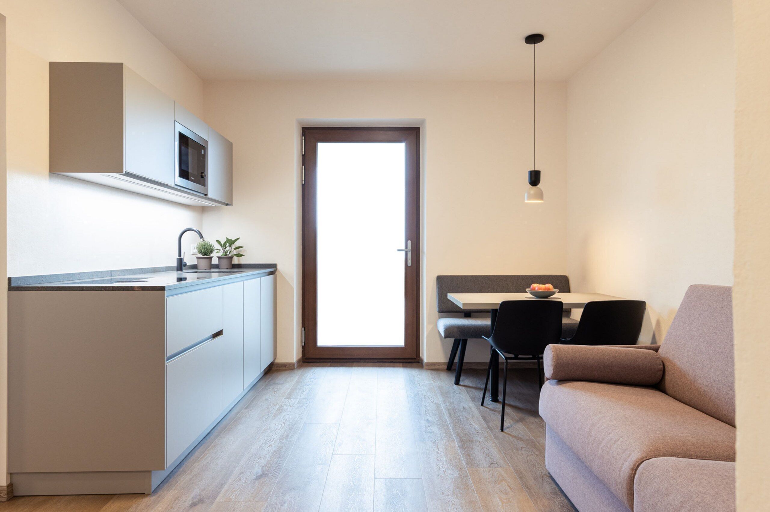 Une cuisine compacte équipée d’un four à micro-ondes, un coin repas avec une table et des chaises, et un canapé.