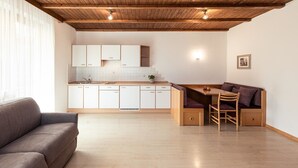 A modern kitchen with white cabinets, a wooden dining table, and a built-in bench. - 724C Residence Hofgarten (Caldaro sulla strada del vino)