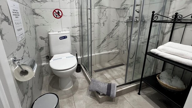 Une salle de bain comprenant des toilettes, un espace douche, un lavabo et un porte-serviettes.