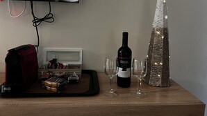 Une table en bois avec une bouteille de vin, deux verres, un plateau de collations et un sapin de Noël décoratif.