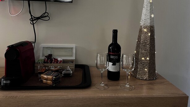 Ein Holztisch mit einer Weinflasche, zwei Gläsern, einer Snackplatte und einem dekorativen Weihnachtsbaum.