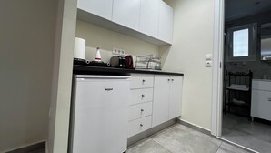 Eine kleine Küche mit integriertem Kühlschrank, einer Arbeitsfläche mit Wasserkocher, Toaster und einem kleinen Spülbecken.