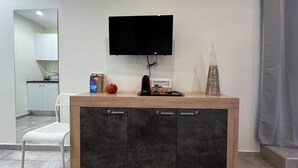 Eine moderne Küche mit integriertem Fernseher, einem weißen Stuhl und einer Zierpflanze.