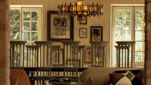 Amplia sala de estar con un gran candelabro, un conjunto de sofás y un comedor con un alto cercado de madera.