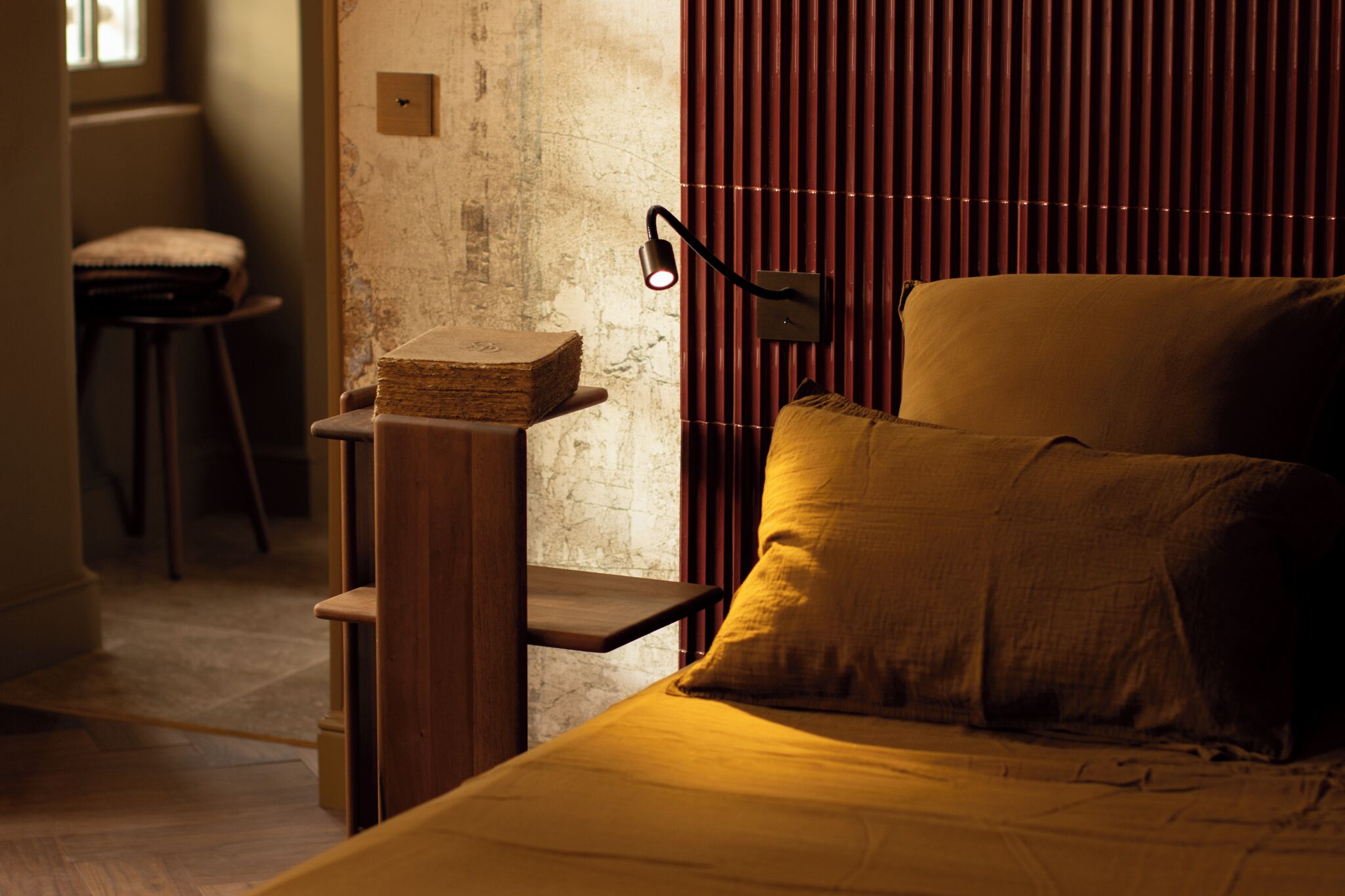 A bedroom with a bed, a nightstand, a lamp, and a window with blinds.