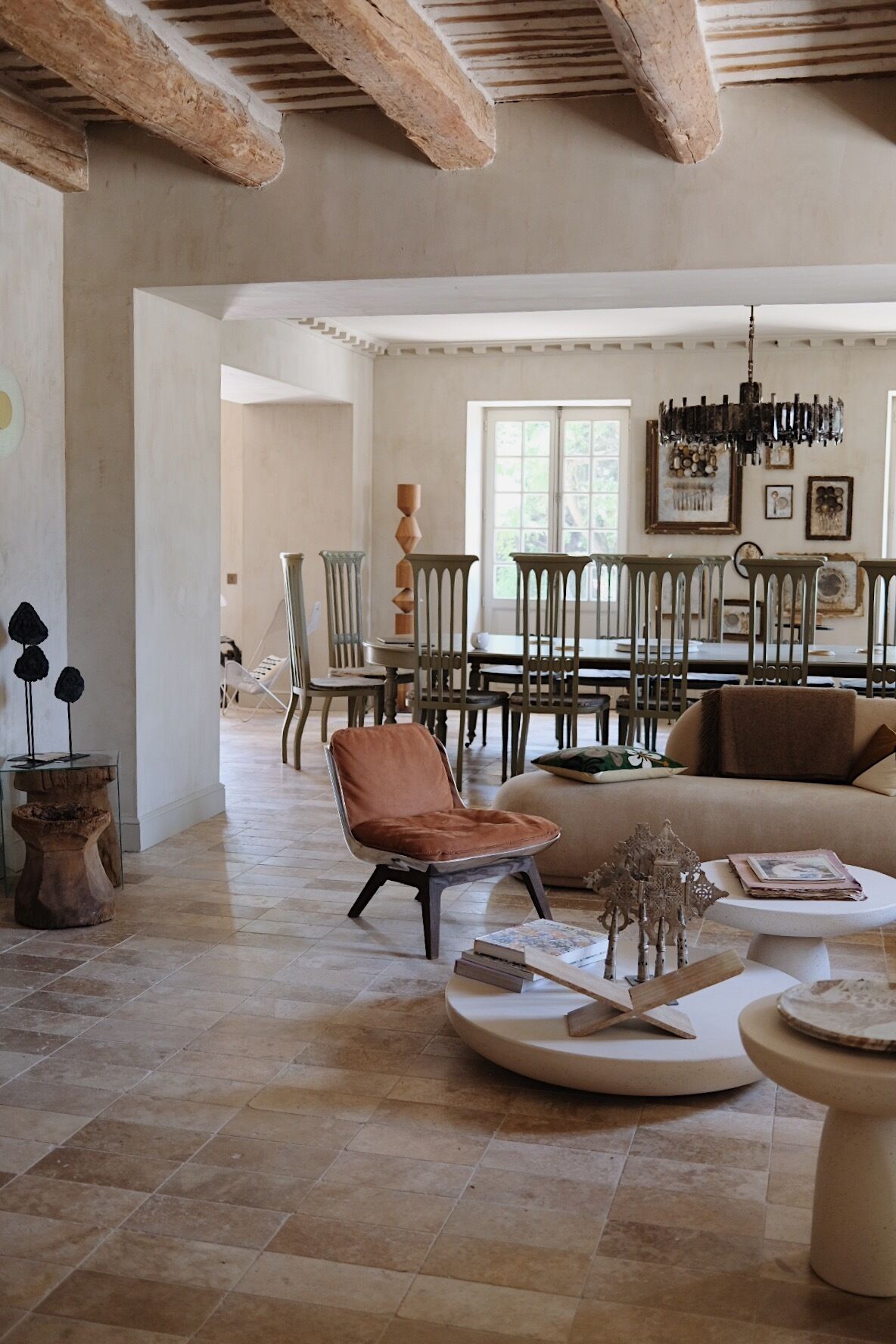 A spacious living room with a high ceiling, a dining area with wooden chairs and a table, and a cozy seating area with a sofa and a coffee table.