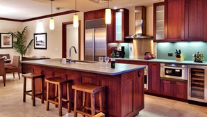 A modern kitchen with a central island, bar stools, stainless steel appliances, and wooden cabinetry. - 3br + 2br on the Same Floor - Sleeps 13! Amazing for Families (Kapolei)