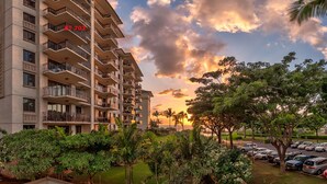 A high-rise hotel with multiple balconies, a parking lot, and a sunset view. - 3br + 2br on the Same Floor - Sleeps 13! Amazing for Families (Kapolei)