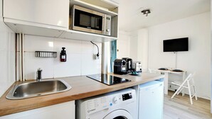 A compact kitchen with a microwave, coffee maker, and washing machine.