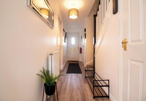Stylish hallway with a door leading to a space, featuring a potted plant and a convenient storage rack.