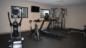 Une salle de sport équipée de divers appareils d’exercice, notamment des tapis de course, un vélo elliptique et une machine de musculation.