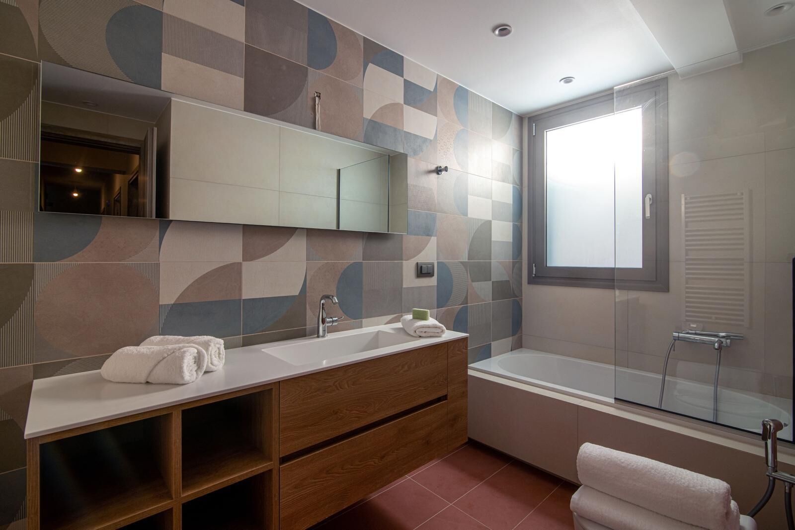 A modern bathroom with a large mirror, a sink, a vanity, and a bathtub.