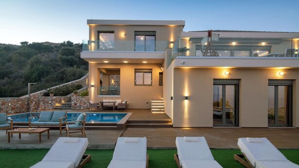 Una casa moderna de dos pisos con piscina, mobiliario exterior y vistas del paisaje circundante.